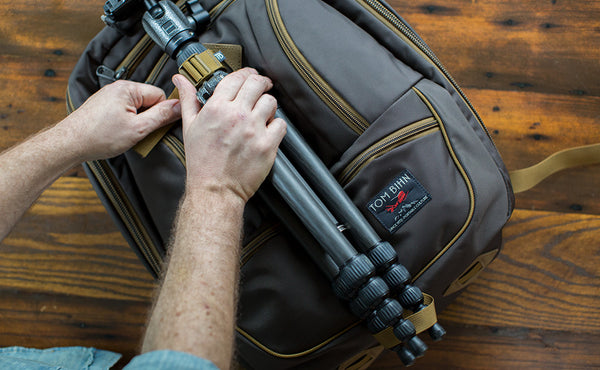 A person lashing a tripod to the face of a Guide's Edition Synik 30 using the front lashpoint and ice axe loop.